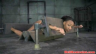 Bound ebony sub in pillory gets spanked